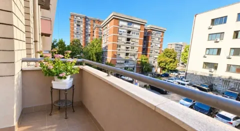 Manji balkon sa saksijom cveća i pogledom na gradske zgrade i parking. - image 13