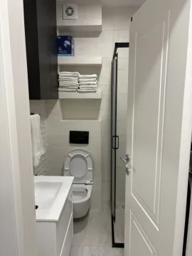 Moderno kupatilo sa tuš kabinom, lavaboom i toaletom viđeno kroz otvorena vrata. - image 12