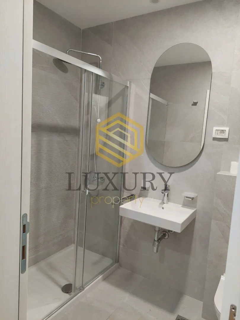 Modern bathroom with a shower cabin, sink and mirror.
