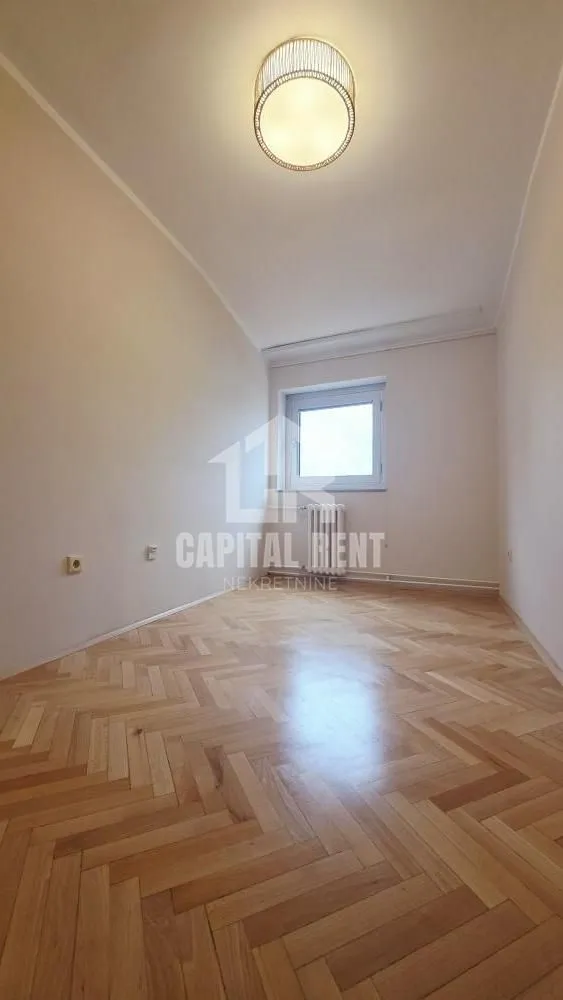 Empty room with parquet flooring and ceiling lighting.