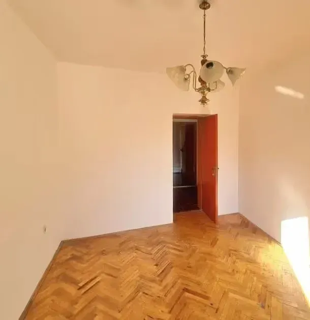 Empty room with parquet flooring and a chandelier.