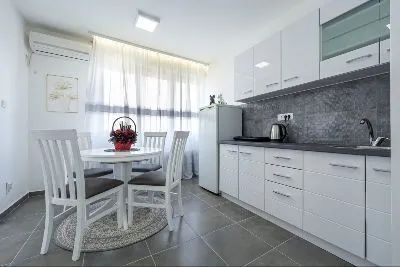 Modern kitchen with dining area and white cabinets. - image 4