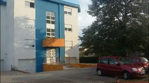 Exterior of a residential building with a blue and white facade and parking. - image 6