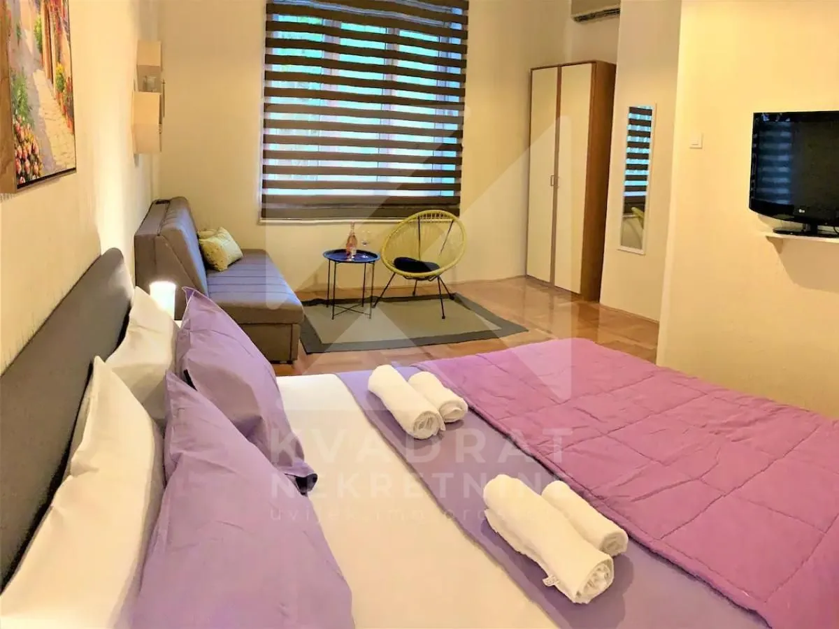 Furnished bedroom with a double bed, a sofa, and a TV.