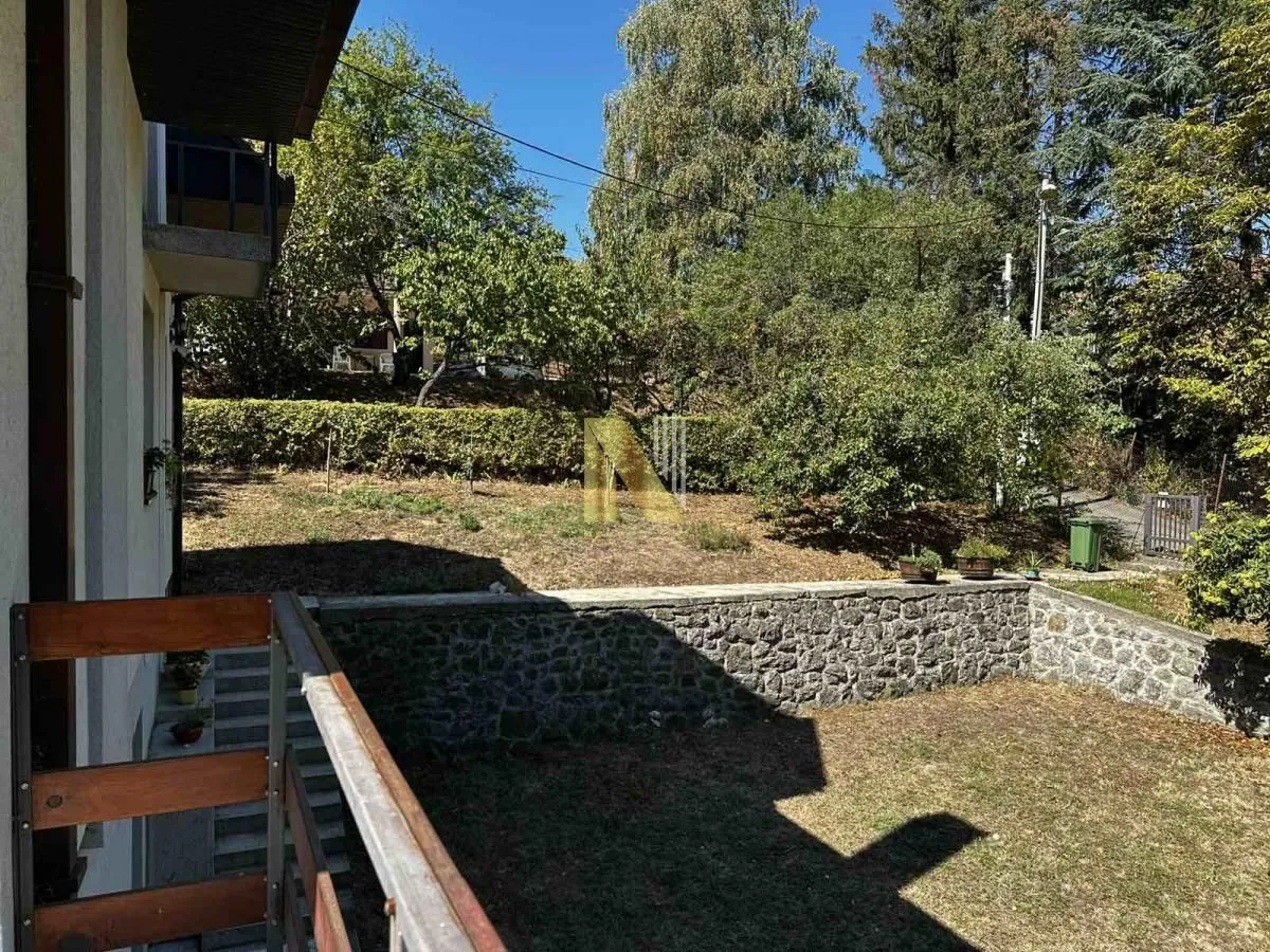 Pogled sa balkona na dvorište i zelene površine.
