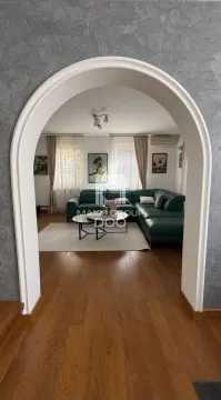 Dnevna soba sa zelenom ugaonom garniturom i pogledom kroz lučni prolaz. - image 4