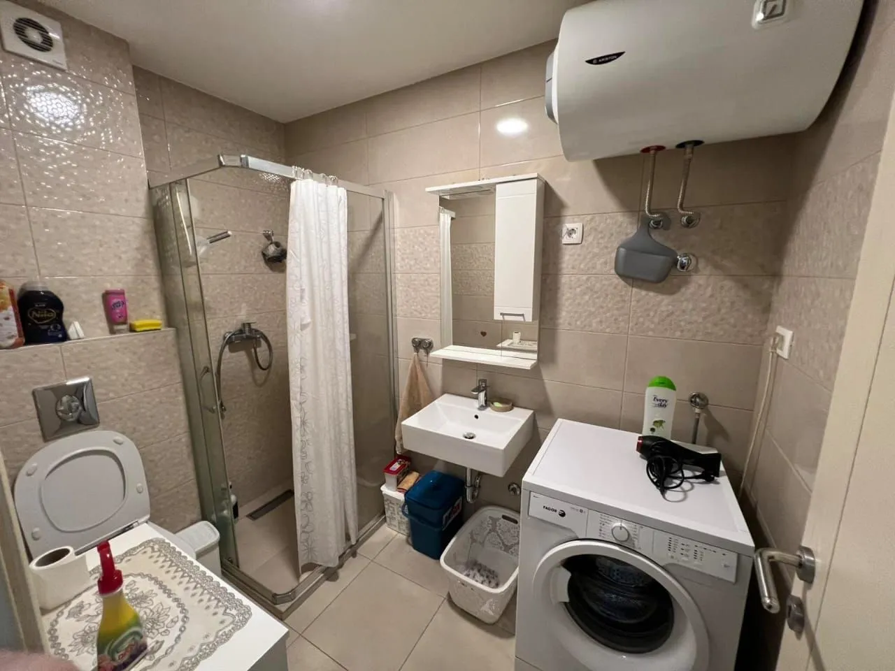 Bathroom equipped with a shower cabin, washbasin, toilet, and washing machine.