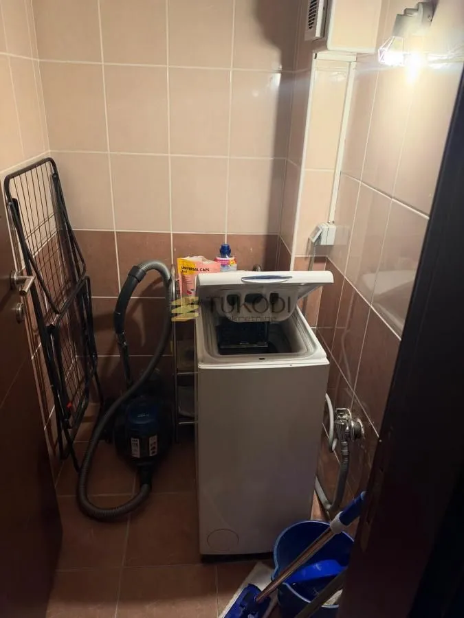 Kupatilo sa veš mašinom i keramičkim pločicama na zidovima.