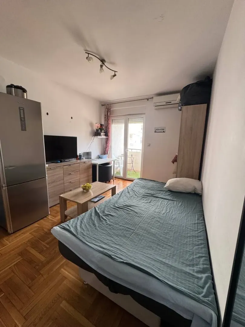 Manja spavaća soba sa krevetom, garderoberom i izlazom na terasu.