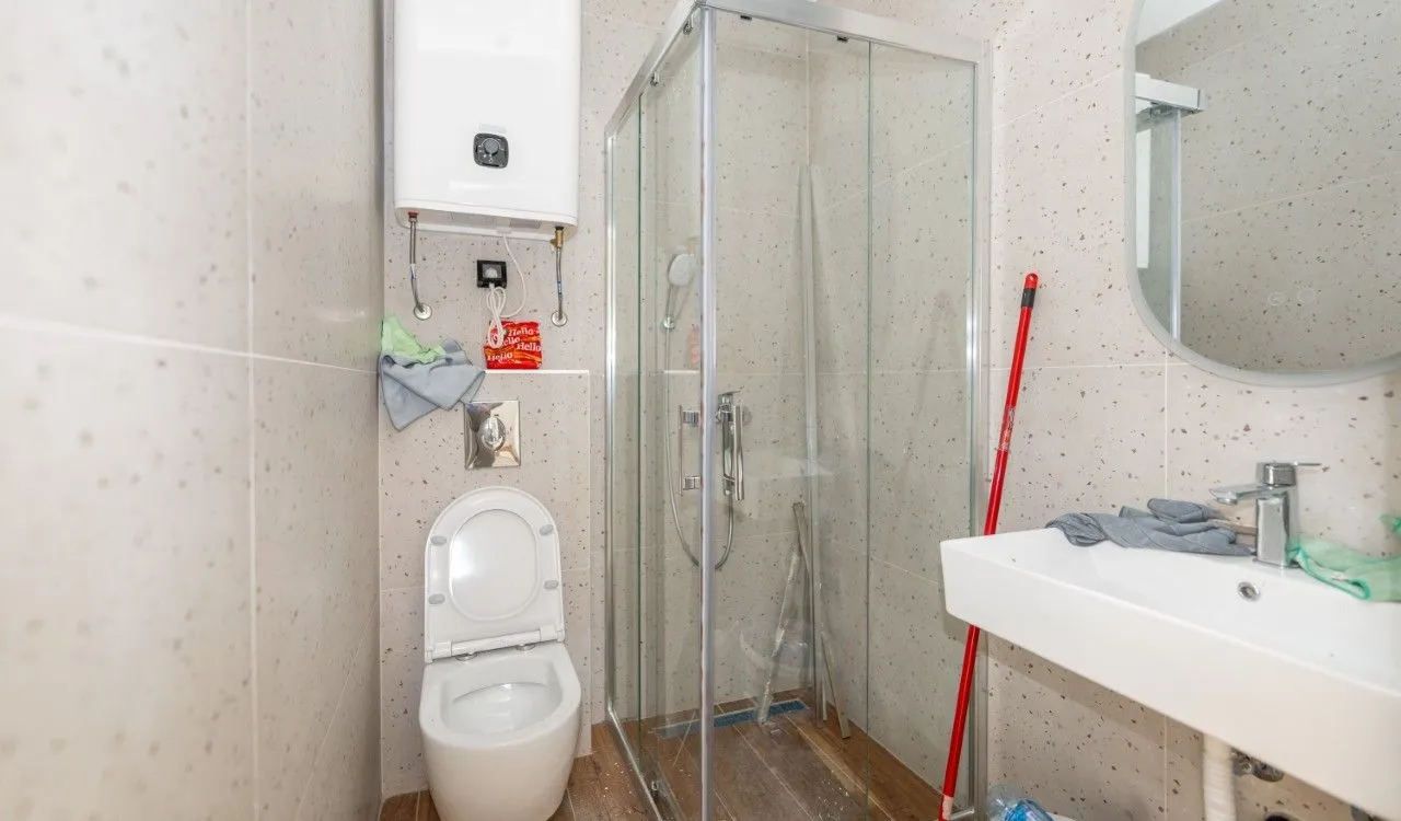 Bathroom with a shower cabin, toilet, washbasin, and water heater.