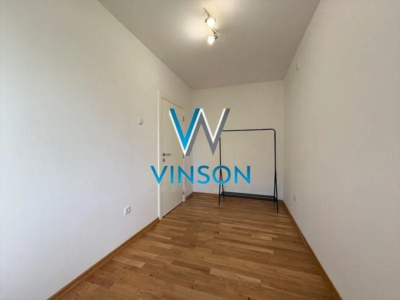Empty room with wooden flooring and a clothing rack.