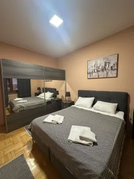 Uređena spavaća soba sa bračnim krevetom i velikim ormarom sa ogledalom. - image 10