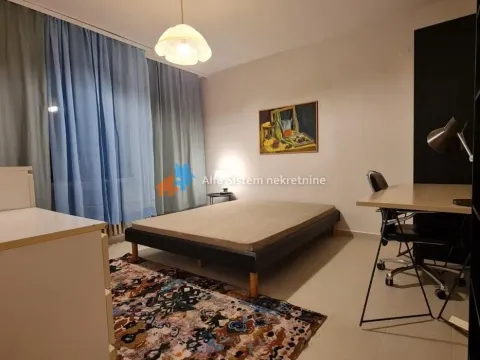 Furnished bedroom with a double bed, desk, and blue curtains. - image 18