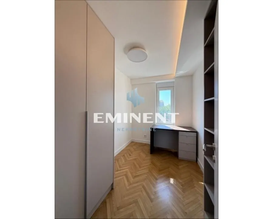 Small bedroom with fitted wardrobes, a desk, and parquet flooring.