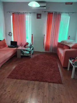 Dnevni boravak sa garniturom, tepihom i prozorima sa narandžastim zavjesama. - image 3