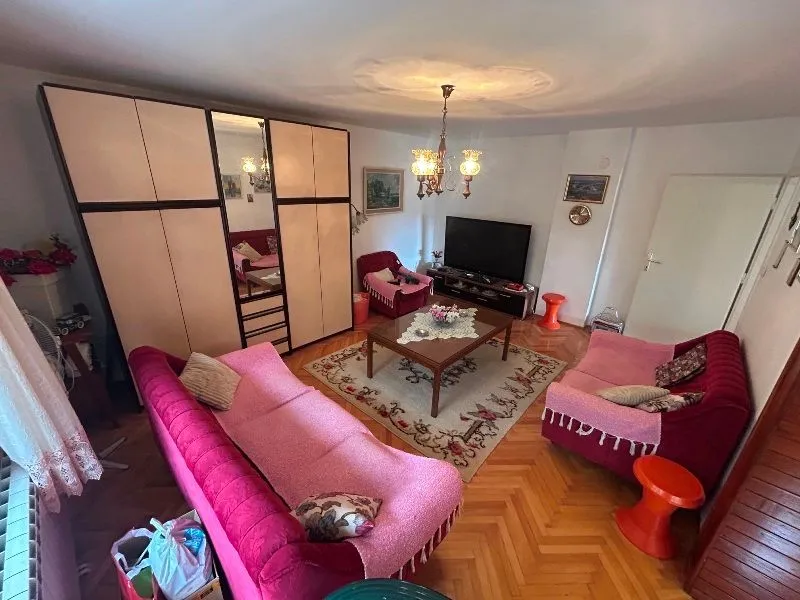 Living room furnished with a wardrobe, seating furniture, and a television.
