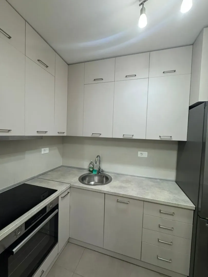 Small modern kitchen with white cabinets and a built-in oven.