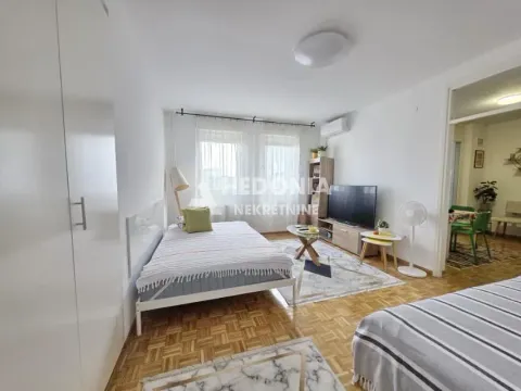 Prostrana spavaća soba sa krevetom, televizorom i garderoberom. - image 3