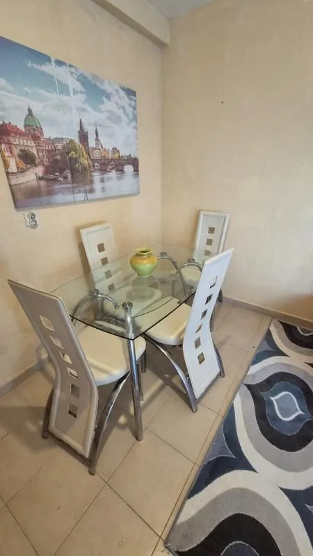 Smaller glass-top dining table with four white chairs in the corner of the room.