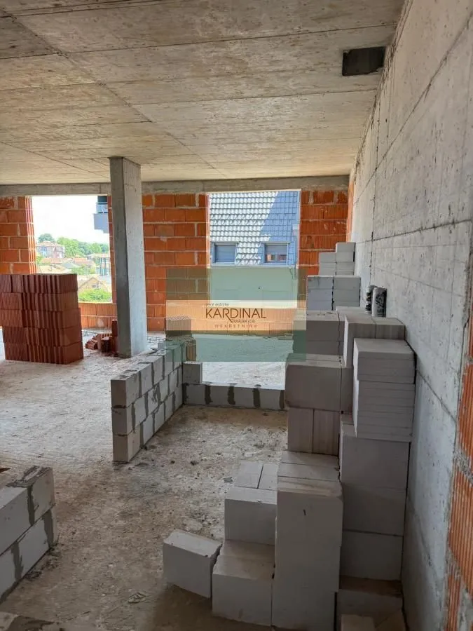 Neuređen enterijer u izgradnji sa betonskim i ciglenim zidovima.