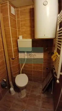 Manje kupatilo obloženo smeđim keramičkim pločicama sa wc šoljom i bojlerom. - image 9