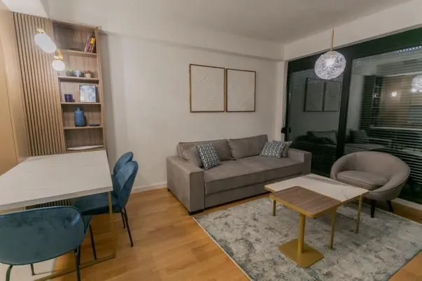 Modern and bright living room with a sofa, dining table, and shelving unit.