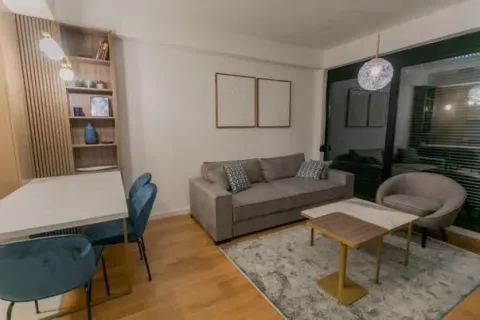 Modern and bright living room with a sofa, dining table, and shelving unit. - image 5