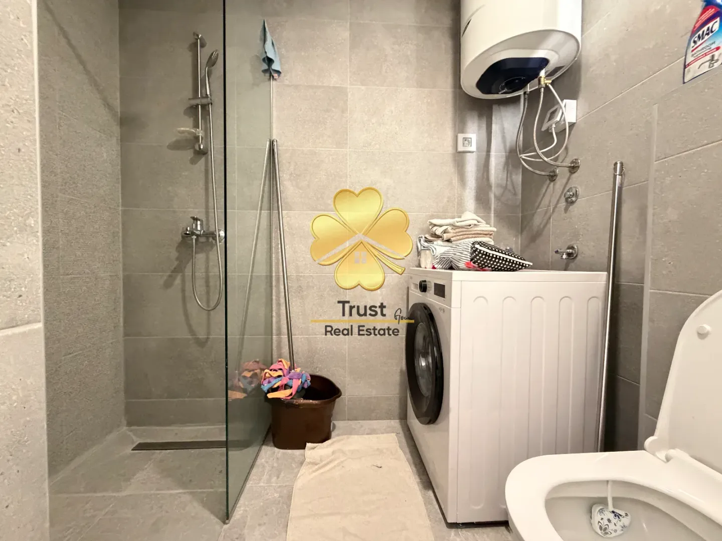 Modern bathroom with a walk-in shower, washing machine, and water heater.