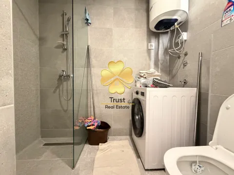 Modern bathroom with a walk-in shower, washing machine, and water heater. - image 10
