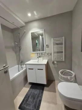 Moderno kupatilo sa kadom, umivaonikom i toaletom u sivo-belim tonovima. - image 3