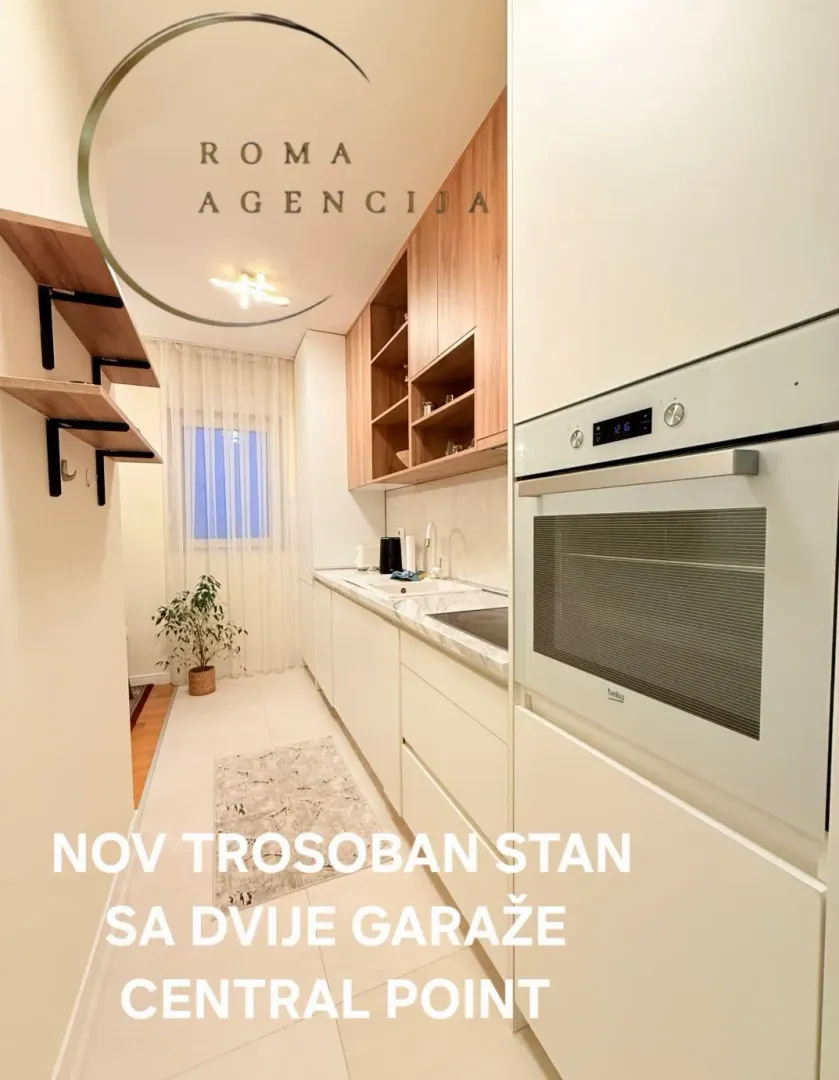 Modern white kitchen with built-in oven and wooden elements.