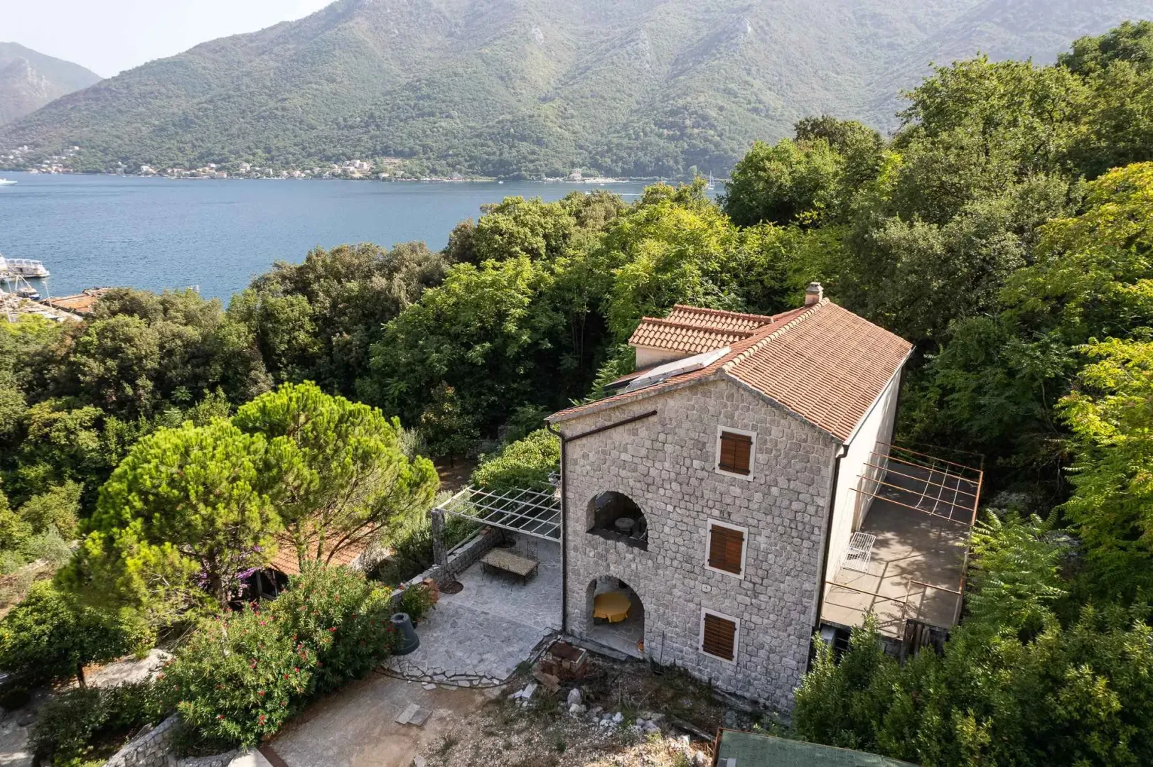 Pogled iz vazduha na kamenu kuću sa dvorištem i pogledom na more.