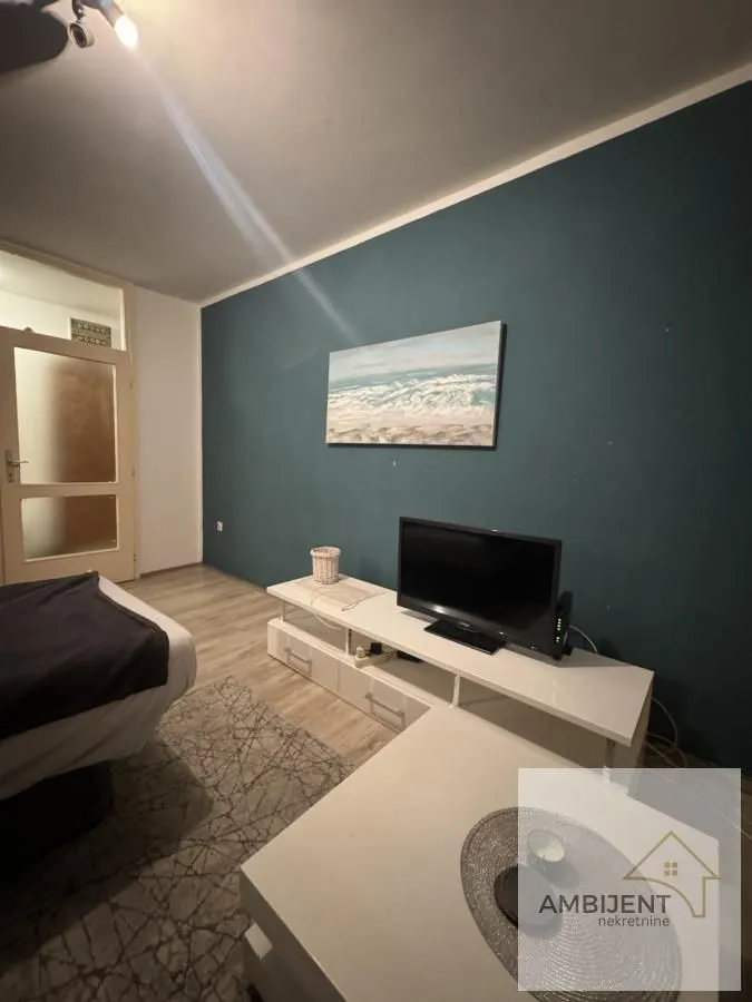 Dnevna soba sa belom TV komodom i plavim zidom.
