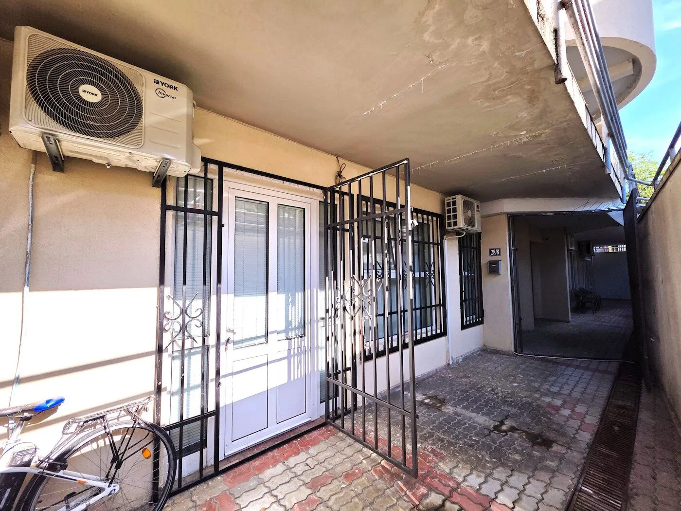 Entrance to the apartment with security bars and an air conditioner on the facade.