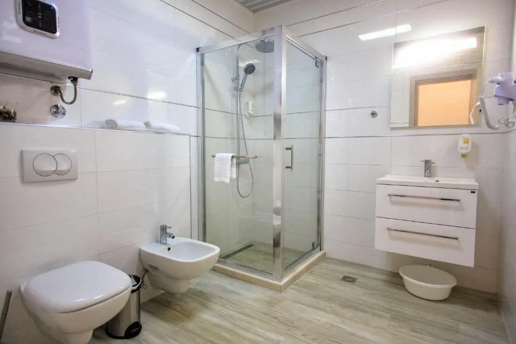 Svijetlo opremljeno kupatilo sa tuš kabinom, umivaonikom i sanitarijama.