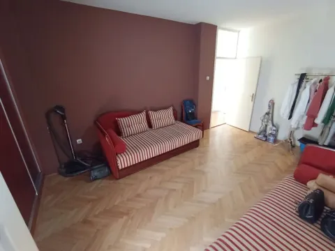 Dnevna soba sa crvenim kaučem, parketom i otvorenim prostorom ka hodniku. - image 4