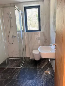 Savremeno opremljeno kupatilo sa tuš kabinom, umivaonikom i wc šoljom. - image 5