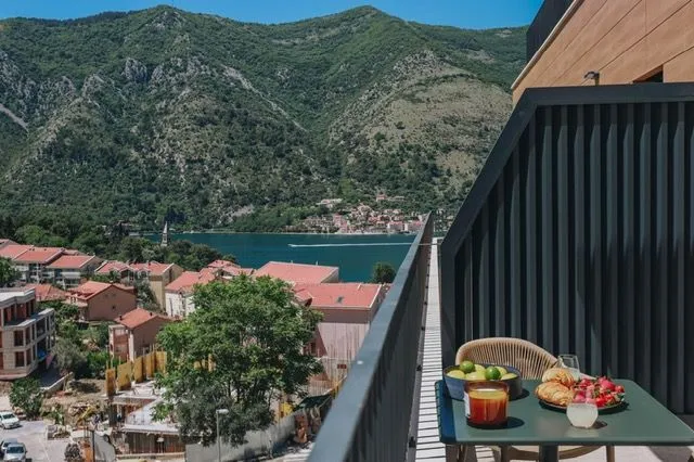 Modern balcony space with a table and a view of the sea and mountains.