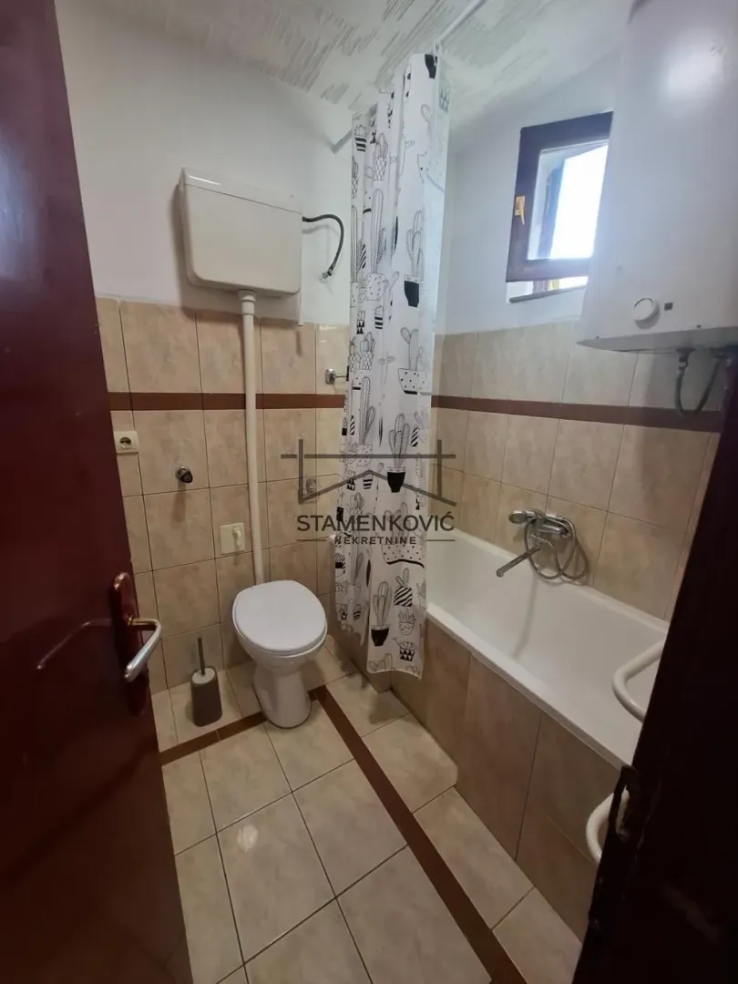 Smaller bathroom with a bathtub, toilet, and water heater.