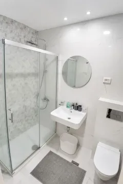 Modern bathroom equipped with a shower cabin and washbasin. - image 10