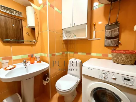 Manje kupatilo sa umivaonikom, toaletom i mašinom za veš, obloženo narandžastim pločicama. - image 15