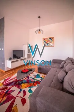 Living room with a sectional sofa, TV, and a colorful rug. - image 3
