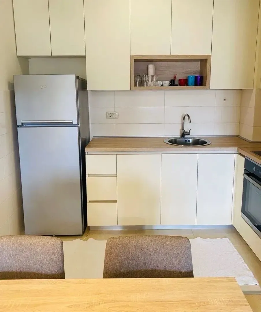 Compact kitchen with white cabinetry, a refrigerator, and a built-in sink.