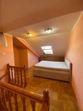 Potkrovna spavaća soba sa bračnim krevetom, krovnim prozorom i drvenim stepeništem. - image 4