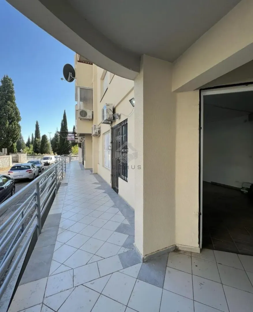 Covered balcony with tiled floor and railing along the building.