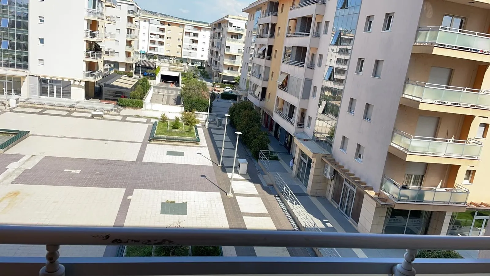 Pogled sa balkona na popločani trg i okolne stambene zgrade.