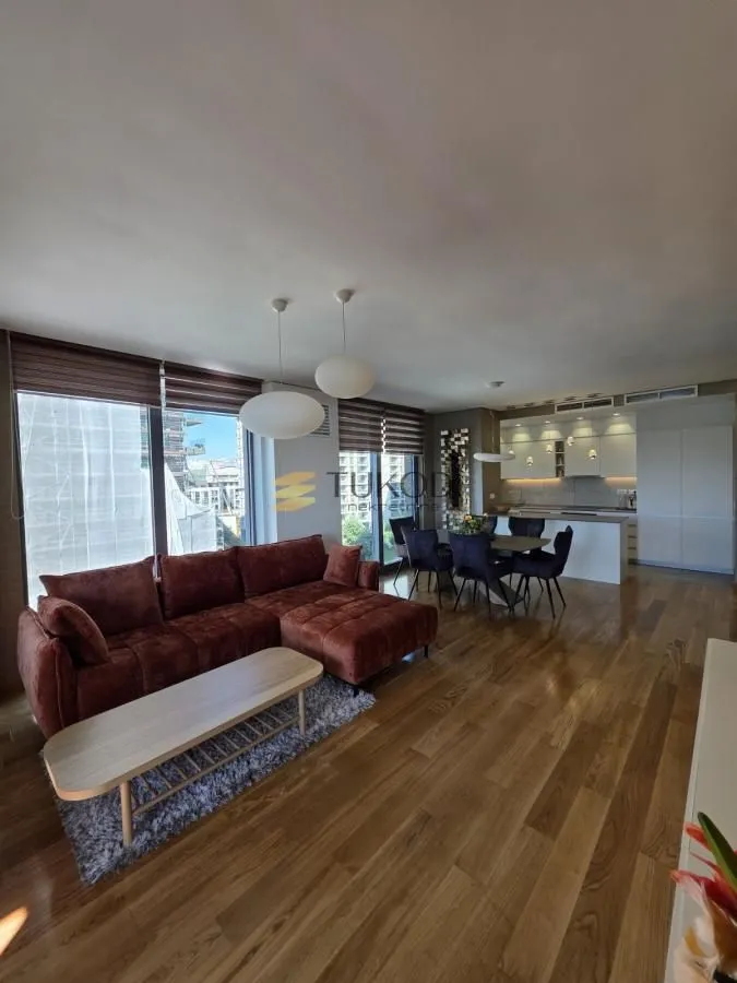 Spacious living room with a sofa, dining area, and kitchen in the background.