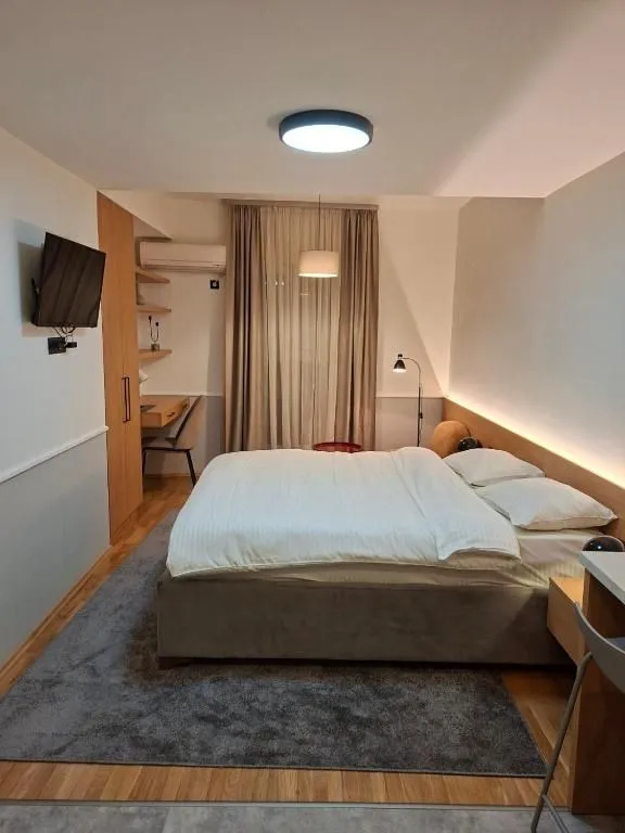 Furnished bedroom with a double bed and a desk.