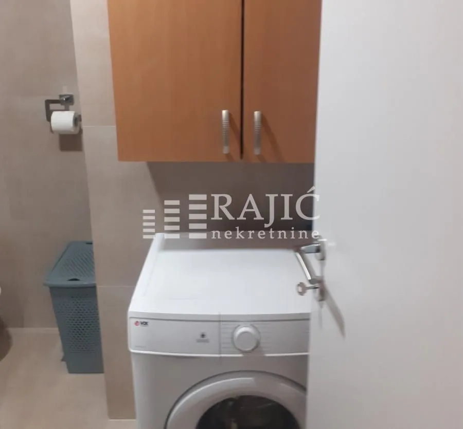 View of a part of the bathroom with a washing machine and a cabinet.