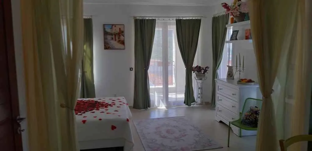 Svijetla spavaća soba sa francuskim balkonom i dekorisanim krevetom.